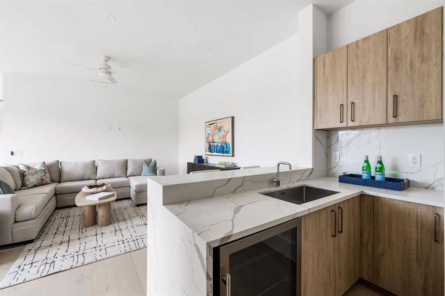 Kitchen featuring beverage cooler, a sink, open floor plan, light stone countertops, and tasteful backsplash