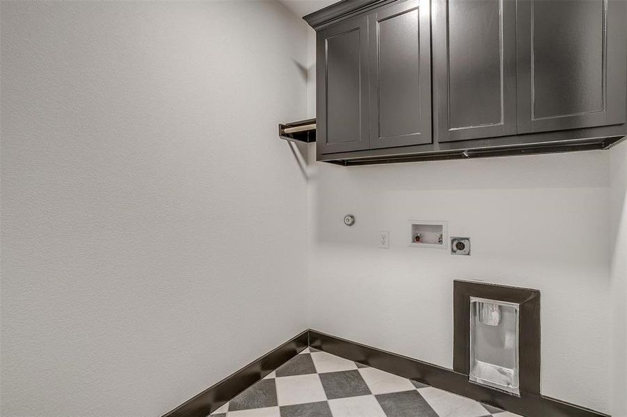 Clothes washing area with gas dryer hookup, tile flooring, hookup for a washing machine, electric dryer hookup, and cabinets