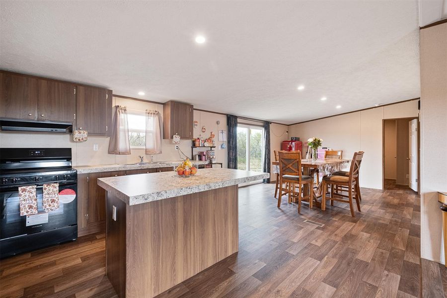 Kitchen featuring black range with electric stovetop, light countertops, healthy amount of natural light, a center island, and crown molding