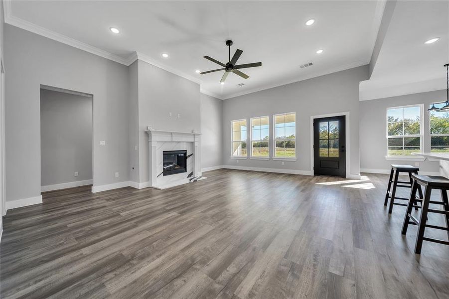 Unfurnished living room featuring a fireplace, dark hardwood / wood-style floors, ceiling fan, and ornamental molding