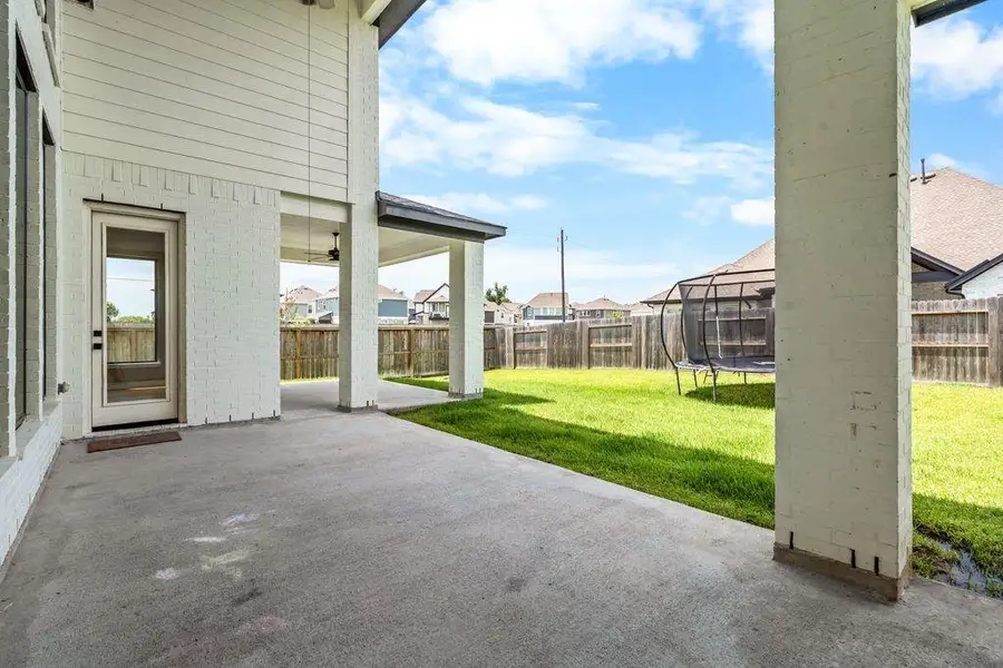 Spacious covered patio overlooking a lush backyard, perfect for outdoor activities and relaxation.