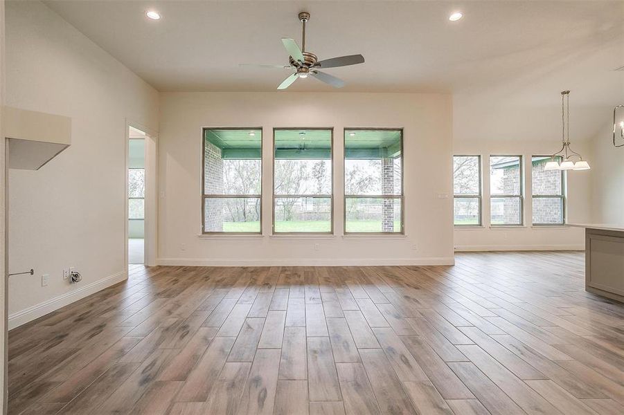 Unfurnished living room with wood-type flooring and ceiling fan with notable chandelier