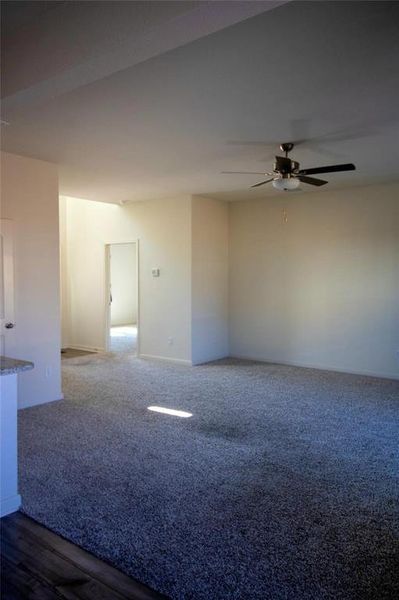 Carpeted empty room featuring ceiling fan and baseboards