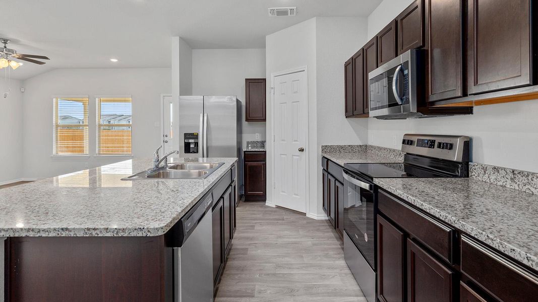 Kitchen featuring stainless steel appliances, dark wood finish cabinets, a ceiling fan, light wood-style floors, and recessed lighting