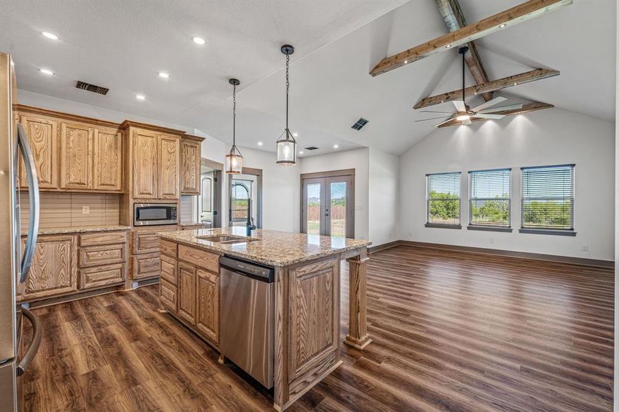 Kitchen with beam ceiling, pendant lighting, decorative backsplash, dark wood-style flooring, and appliances with stainless steel finishes