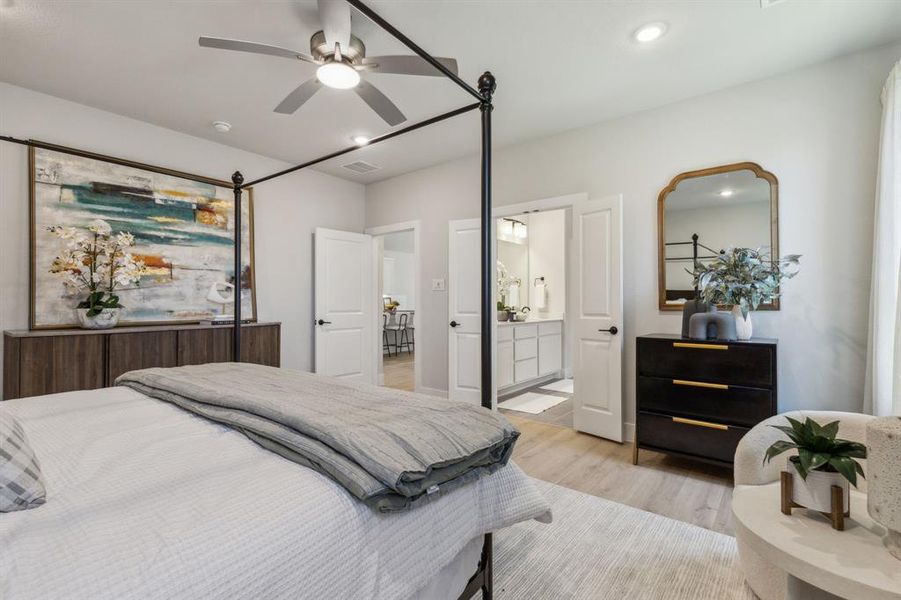 Bedroom featuring light hardwood / wood-style floors, ceiling fan, and ensuite bath