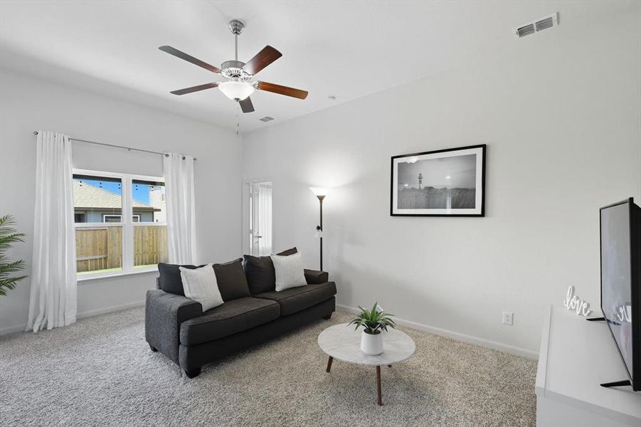 Carpeted living room featuring baseboards and ceiling fan