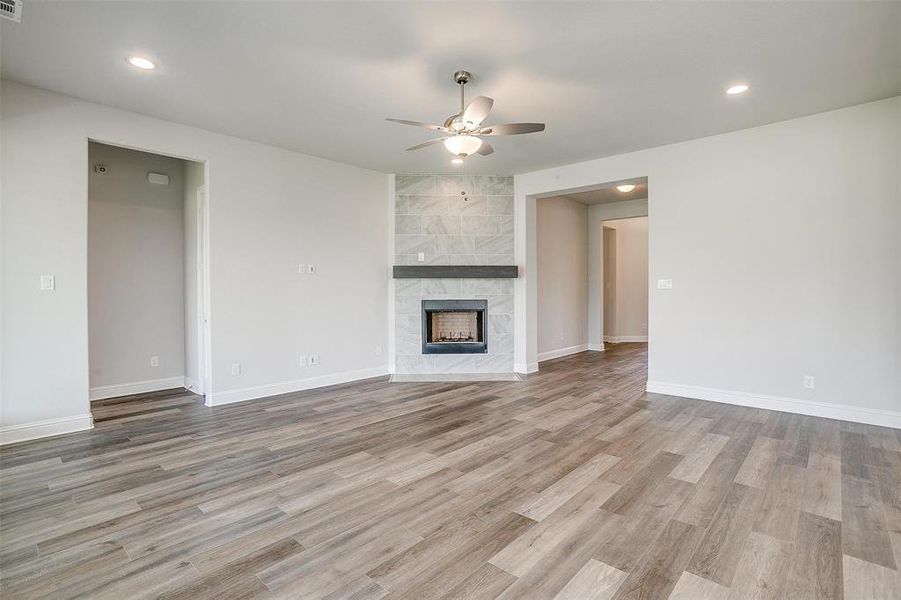 Unfurnished living room featuring ceiling fan, light hardwood / wood-style flooring, tile walls, and a fireplace