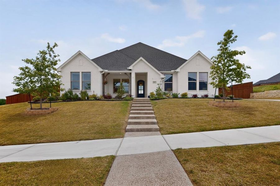 Contemporary ranch-style home featuring a white brick exterior and dark shingle roof Contemporary ranch-style home featuring a white brick exterior and dark shingle roof