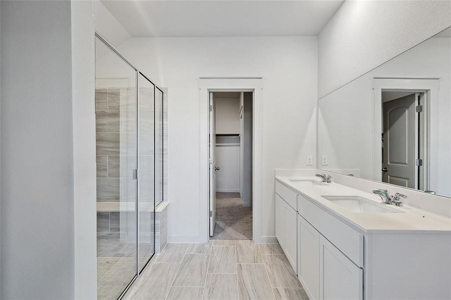 Bathroom featuring a shower with shower door and vanity