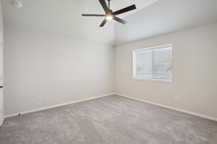 Unfurnished room with carpet flooring, a ceiling fan, vaulted ceiling, baseboards, and a smoke detector