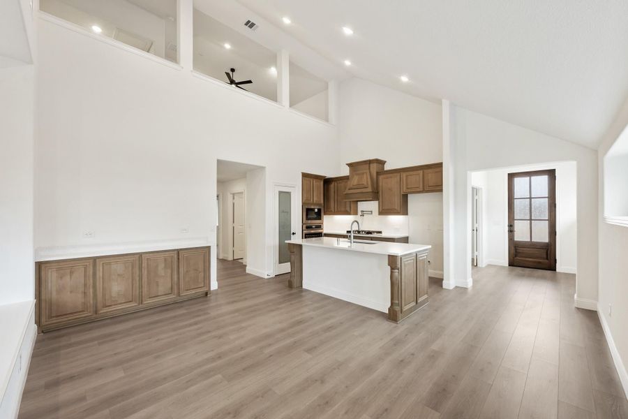 Open-concept kitchen with wood cabinets, center island, and high ceilings over hardwood floors Open-concept kitchen with wood cabinets, center island, and high ceilings over hardwood floors