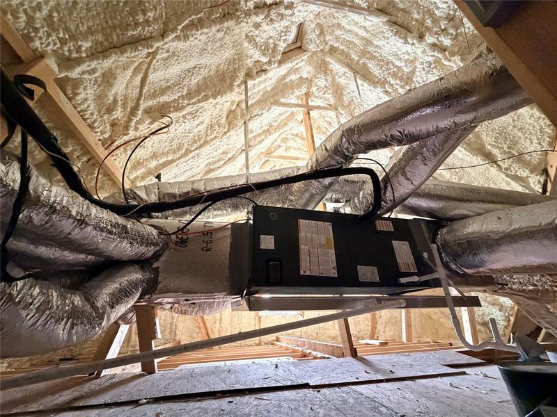 Attic space featuring spray foam insulation, exposed wooden trusses, and installed ductwork Attic space featuring spray foam insulation, exposed wooden trusses, and installed ductwork