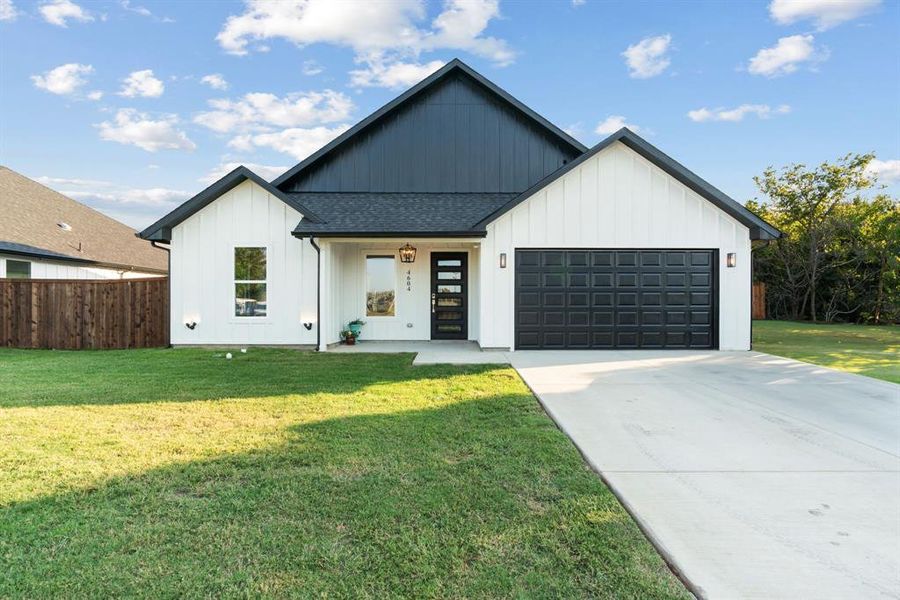 Modern inspired farmhouse featuring a front lawn and a garage