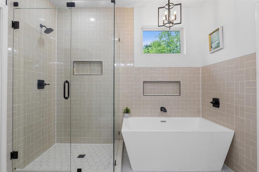 Full bath with tile walls, a stall shower, a freestanding bath, and a chandelier Full bath with tile walls, a stall shower, a freestanding bath, and a chandelier