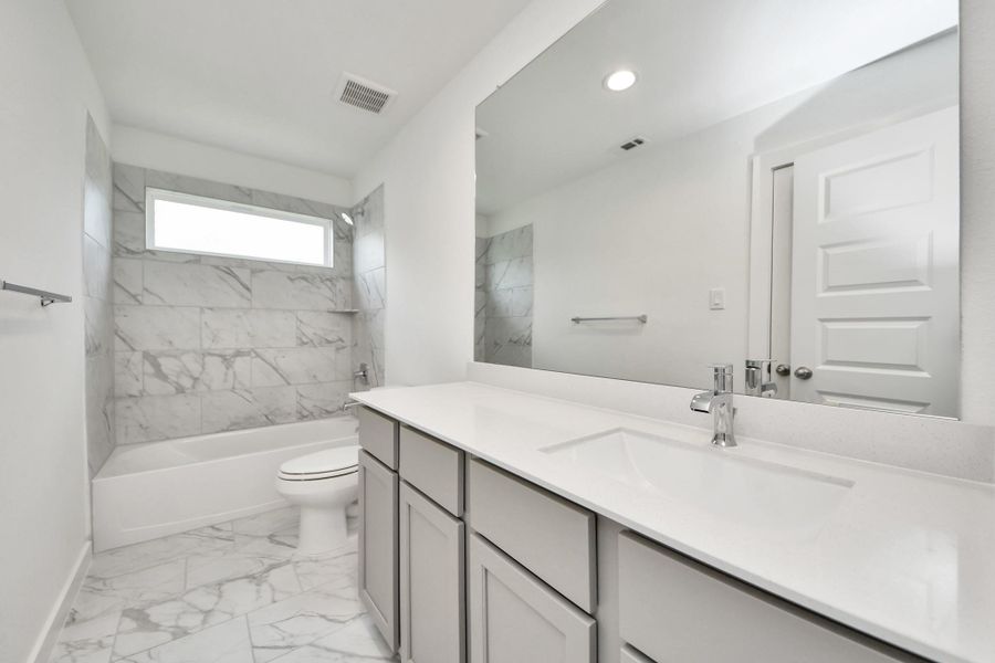 Secondary bath features tile flooring, bath/shower combo with tile surround, light stained wood cabinets, beautiful light countertop. Secondary bath features tile flooring, bath/shower combo with tile surround, light stained wood cabinets, beautiful light countertop.