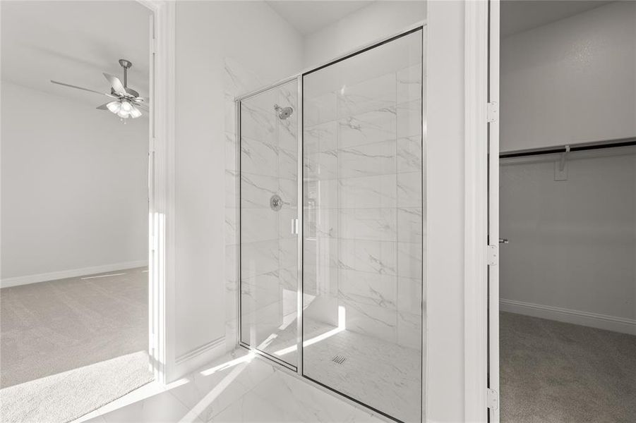 Bathroom featuring ceiling fan and a shower with door