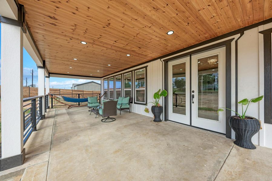 Rich wood plank ceilings and recessed lighting elevate this covered concrete patio. Rich wood plank ceilings and recessed lighting elevate this covered concrete patio.