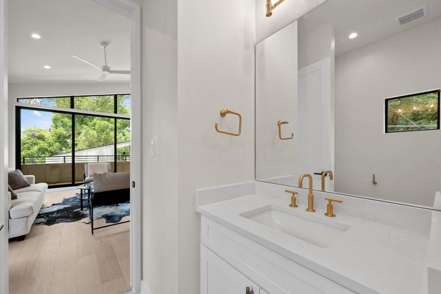A chic bathroom vanity featuring a clean countertop and modern gold fixtures, offering a glimpse into an adjacent living area. A chic bathroom vanity featuring a clean countertop and modern gold fixtures, offering a glimpse into an adjacent living area.