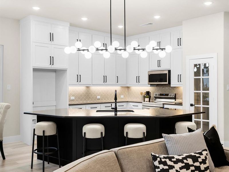 Kitchen featuring appliances with stainless steel finishes, a kitchen bar, light wood finished floors, dark countertops, and recessed lighting
