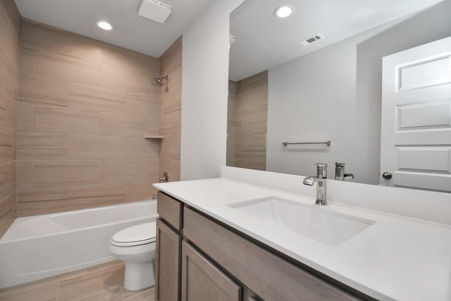 Secondary bath features tile flooring, bath/shower combo with tile surround, light stained wood cabinets, beautiful light countertop. Secondary bath features tile flooring, bath/shower combo with tile surround, light stained wood cabinets, beautiful light countertop.