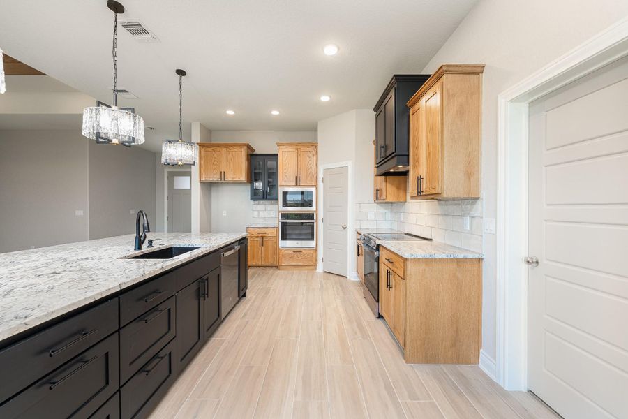 Kitchen featuring pendant lighting, light stone countertops, tasteful backsplash, stainless steel appliances, and recessed lighting Kitchen featuring pendant lighting, light stone countertops, tasteful backsplash, stainless steel appliances, and recessed lighting