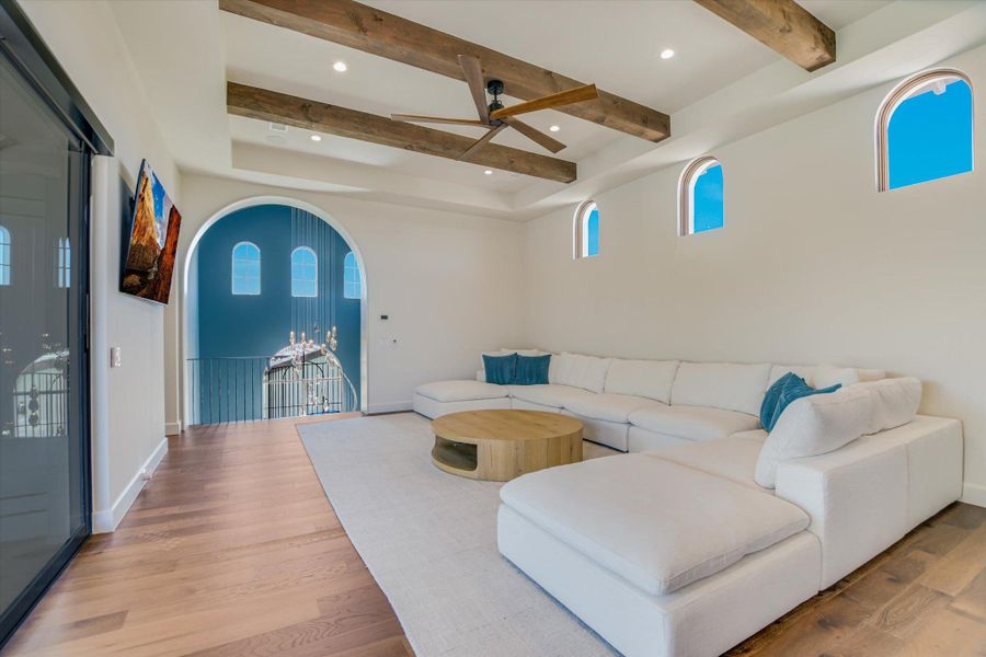 Living room featuring arched walkways, ceiling fan, light wood-type flooring, and recessed lighting