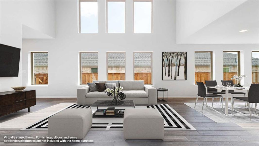 Living room featuring wood-type flooring, plenty of natural light, and a towering ceiling