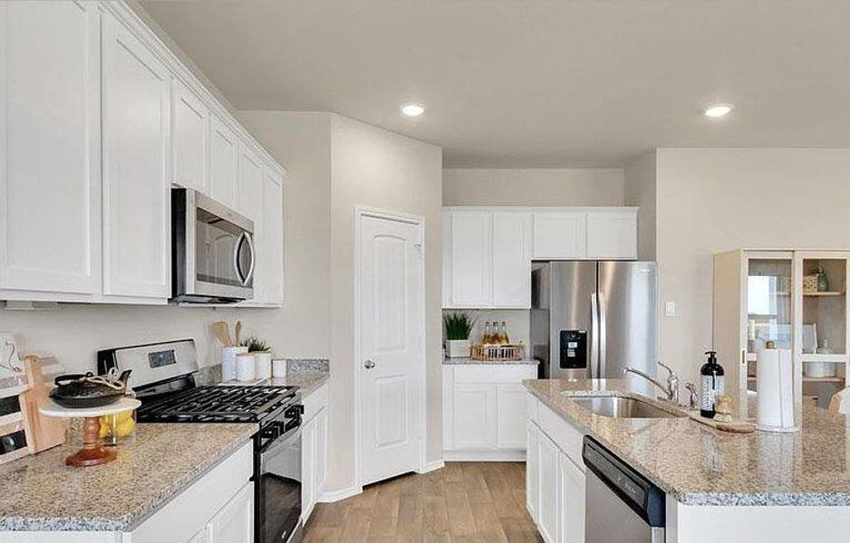 Kitchen with stainless steel appliances, a sink, a kitchen island with sink, light wood-type flooring, and white cabinets Kitchen with stainless steel appliances, a sink, a kitchen island with sink, light wood-type flooring, and white cabinets