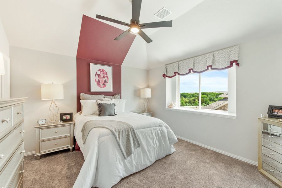 Bedroom with vaulted ceiling, red accent wall, ceiling fan, and carpet flooring Bedroom with vaulted ceiling, red accent wall, ceiling fan, and carpet flooring