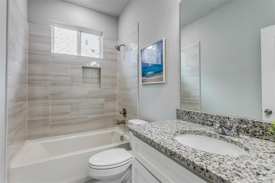 Full bathroom with vanity, tiled shower / bath, and toilet