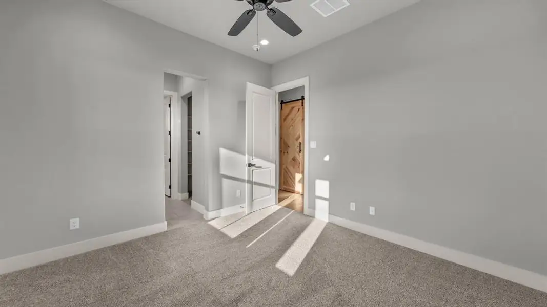 Spacious room featuring neutral carpeting, light gray wall tones, and white baseboards Spacious room featuring neutral carpeting, light gray wall tones, and white baseboards