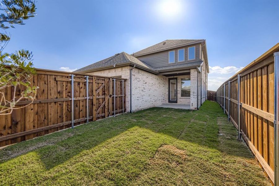 Back of property with a patio, a fenced backyard, a shingled roof, and brick siding