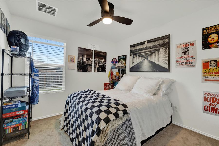 A well-lit sleeping area features neutral carpet and a ceiling fan for comfort.