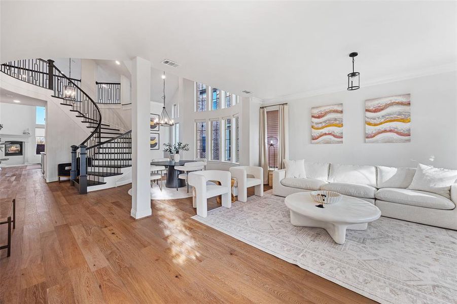 Living room featuring a towering ceiling, visible vents, wood finished floors, stairway, and a chandelier