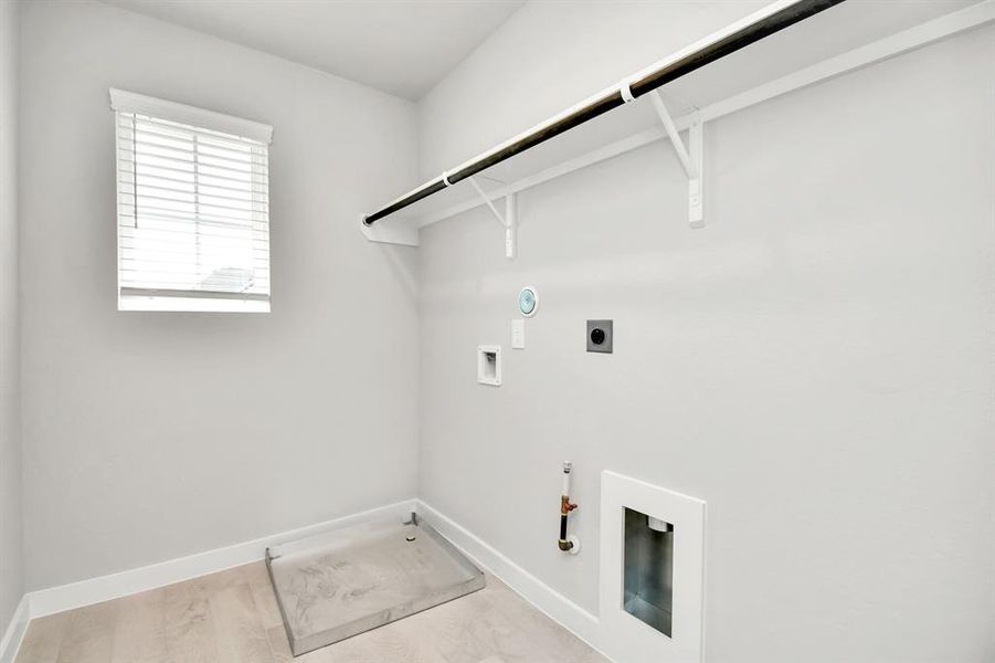 A spacious utility room with ample shelving for organization. It features connections for both gas and electric dryers, making it versatile and functional for all laundry needs. Example photo of completed home with similar plan. Actual may vary.