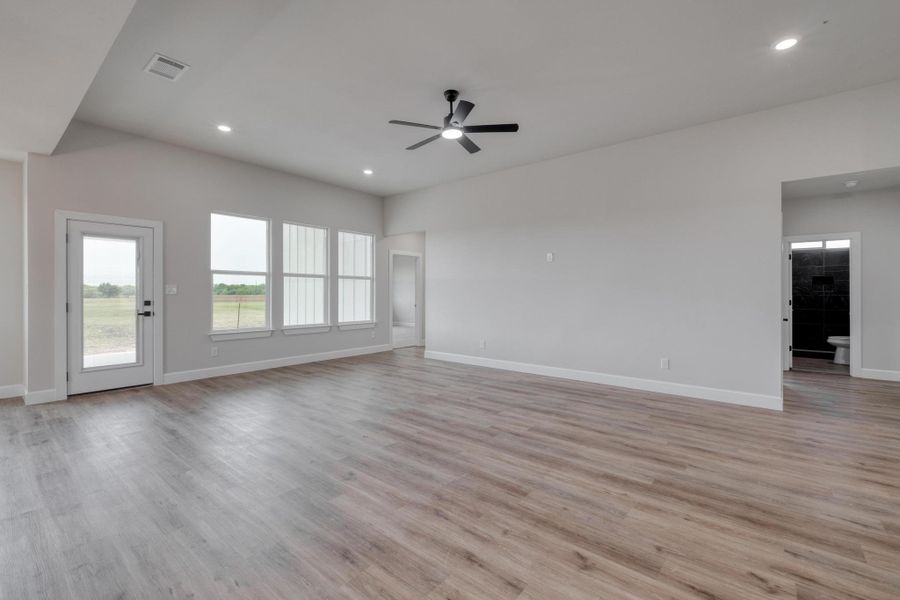 Unfurnished living room featuring a ceiling fan, baseboards, recessed lighting, and light wood-style flooring