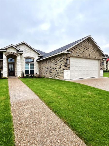 View of front of property featuring an attached garage, a front lawn, brick siding, concrete driveway, and a shingled roof View of front of property featuring an attached garage, a front lawn, brick siding, concrete driveway, and a shingled roof