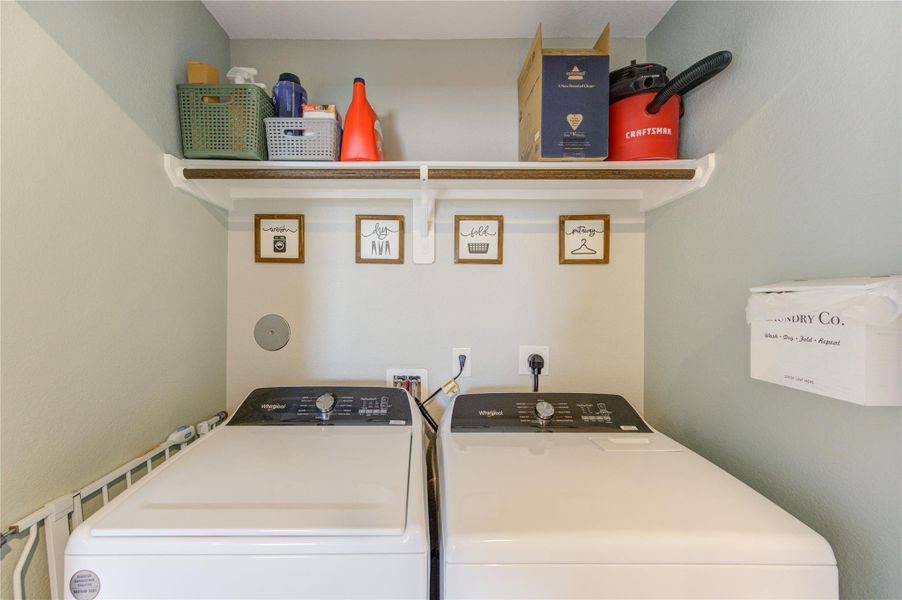This photo showcases a compact laundry room featuring a washer and dryer set. Above them, there are shelves with storage baskets and cleaning supplies, providing practical organization. The space is neatly arranged for efficient laundry use.