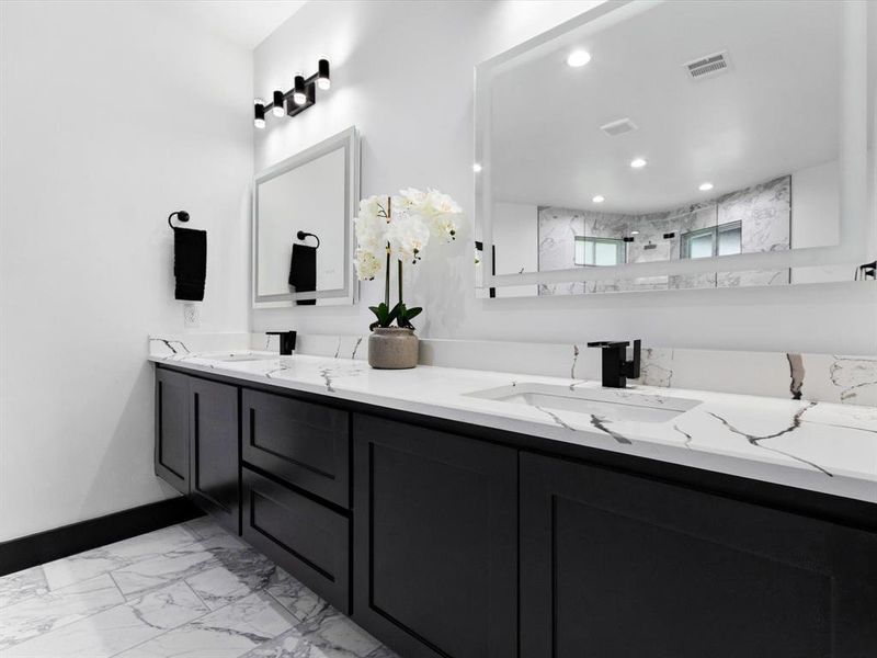 Dual vanity featuring black shaker-style cabinetry, white countertops with prominent veining, and integrated sinks with matte black fixtures