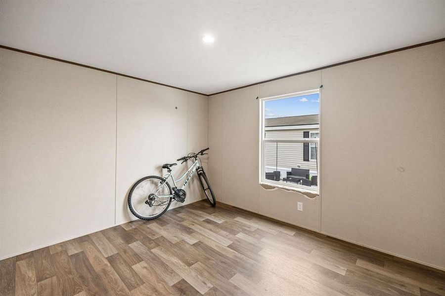 Spacious interior room featuring wood-finish flooring and light-toned walls Spacious interior room featuring wood-finish flooring and light-toned walls