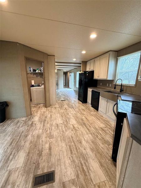 Kitchen featuring black appliances, recessed lighting, light wood-type flooring, white cabinets, and dark countertops