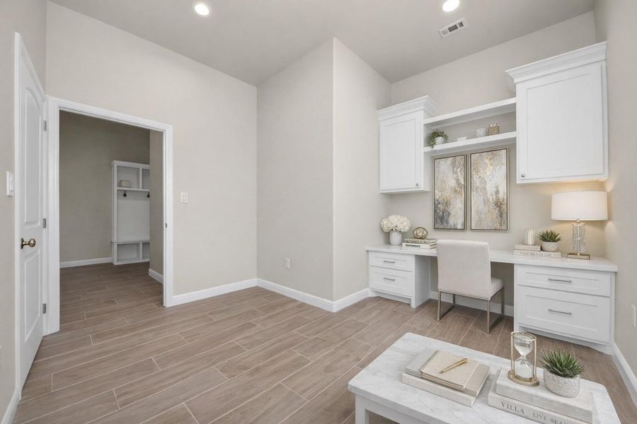 This bright, modern office space with wood look tile flooring and neutral walls, features a built-in white desk with overhead cabinets, Ideal for a home workspace, or convert this to a 5th bedroom.