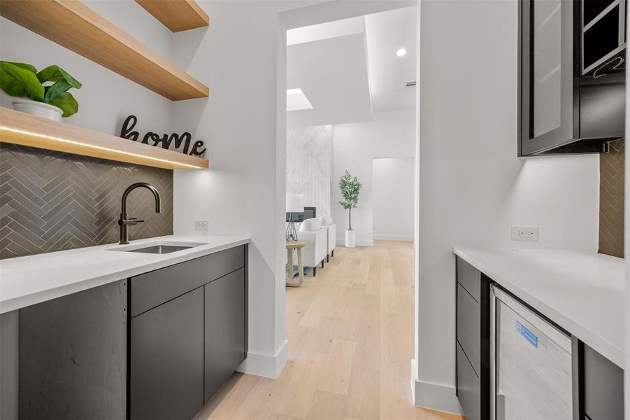A well-appointed wet bar area, featuring sleek countertops, modern cabinetry, and ample storage.