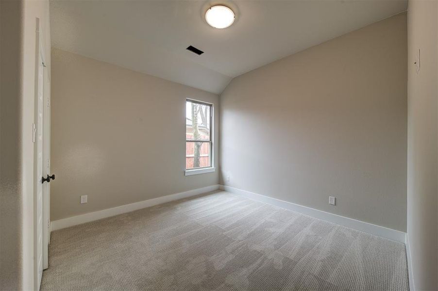 Unfurnished room with lofted ceiling and light carpet