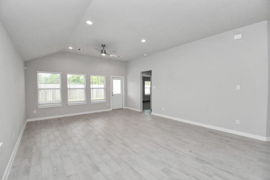 Welcome family and guests to your charming living room! With its high ceilings, recessed lighting, ceiling fan, custom paint, beautiful flooring, and large windows that let in abundant natural light, this room is perfect for gatherings.