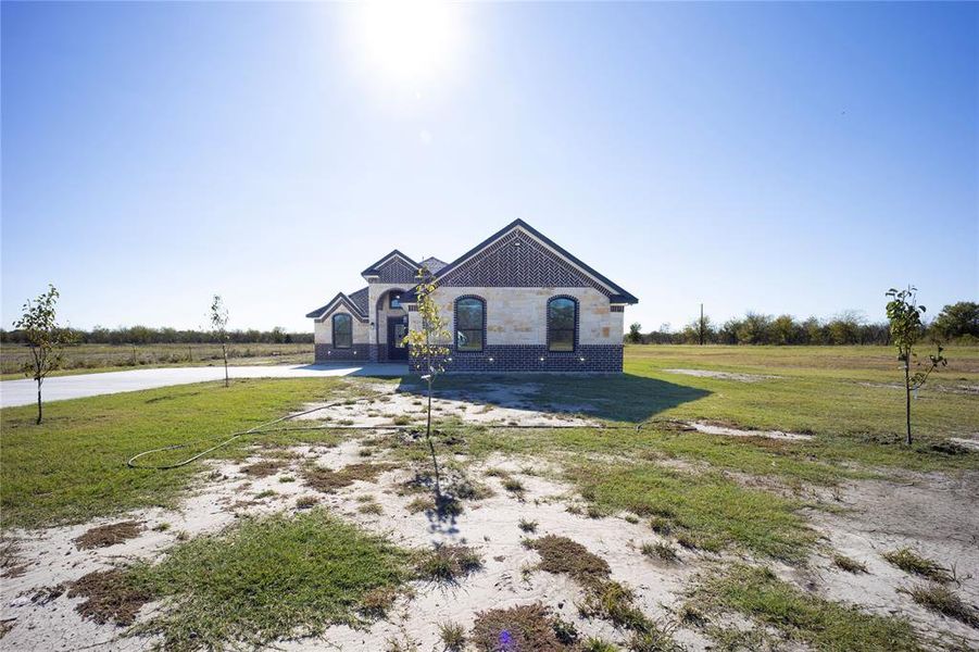 French country home with a front lawn, brick siding, a view of rural / pastoral area, and stone siding