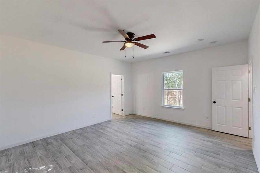 Primary bedroom featuring light hardwood / wood-style flooring and ceiling fan