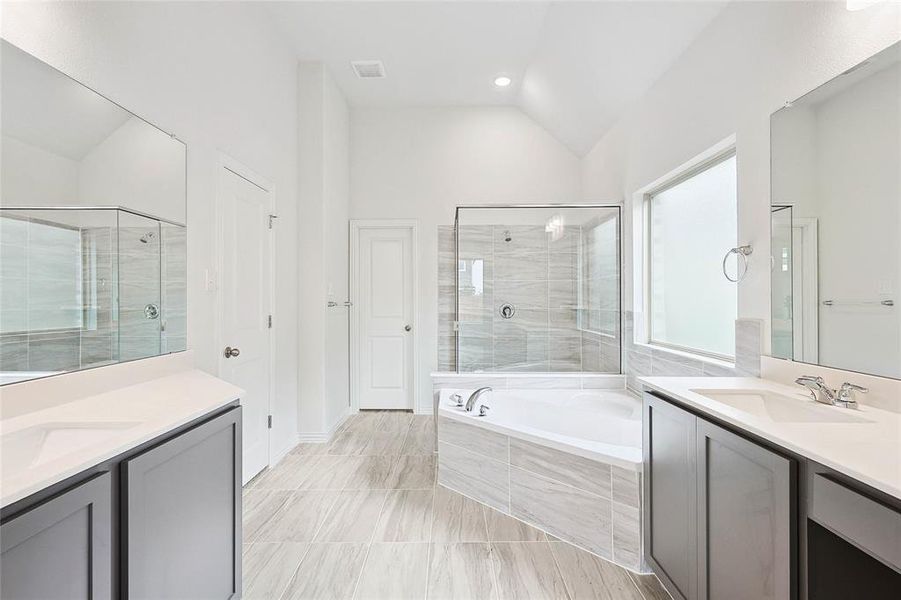 Bathroom with tile floors, lofted ceiling, shower with separate bathtub, and oversized vanity