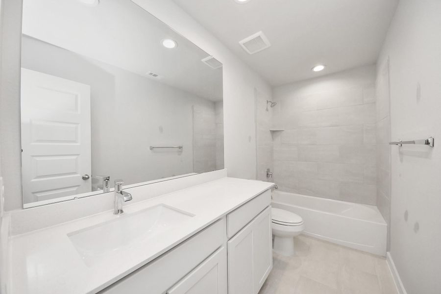 Secondary bath features tile flooring, bath/shower combo with tile surround, light stained wood cabinets, beautiful light countertop. Secondary bath features tile flooring, bath/shower combo with tile surround, light stained wood cabinets, beautiful light countertop.